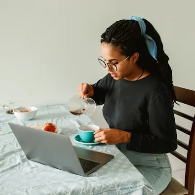 Smilding woman sitting on her couch with a laptop.